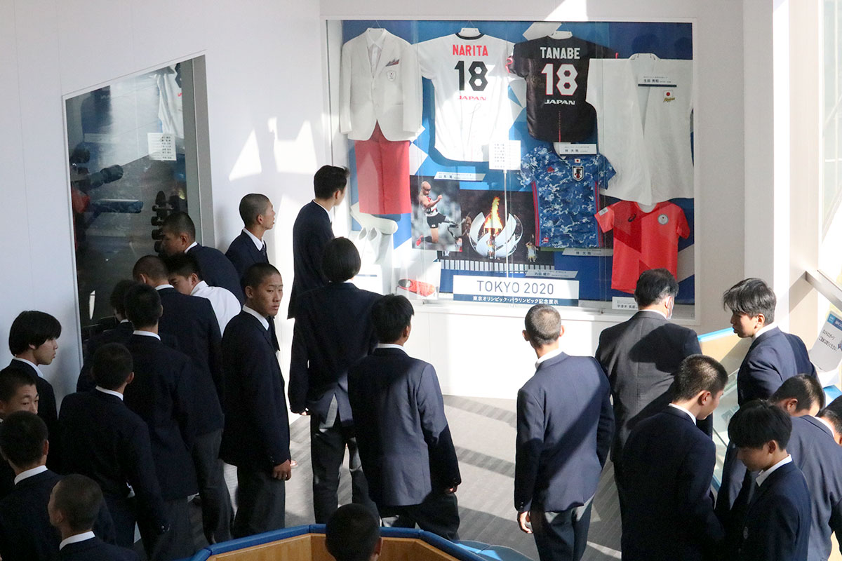東京オリンピック・パラリンピックに出場した本学関係者などの紹介コーナーや本学OBのプロ選手のユニホームやトロフィーなどが並ぶ展示スペースを見る