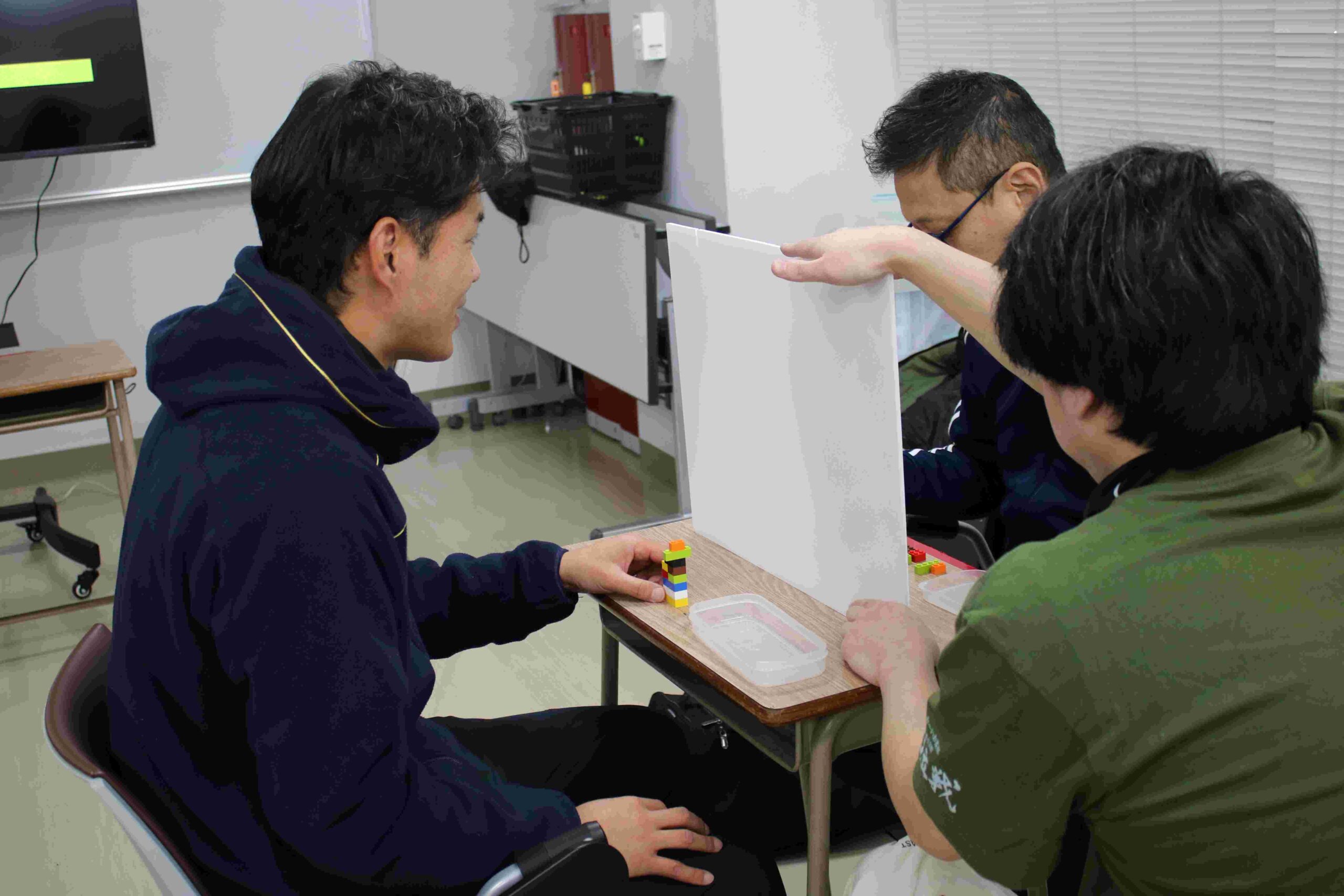コーチ役は自分で組み立てたカラーブロックを言葉だけで伝え、選手役は同じ組み立て方をめざす。的確な指示の伝え方を学ぶ